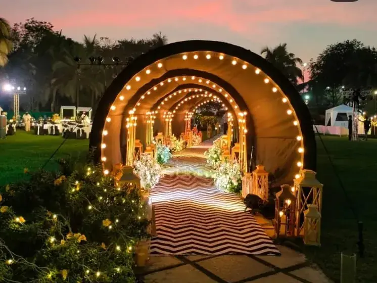 A tunnel of warm lights over a lawn laid out for an evening event