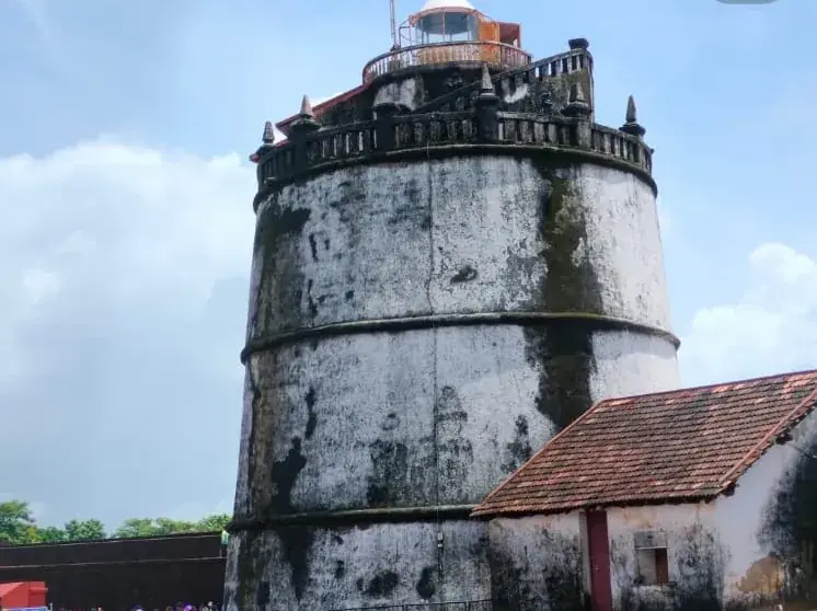 A weathered fort lighthouse under a blue sky on the Goa coast