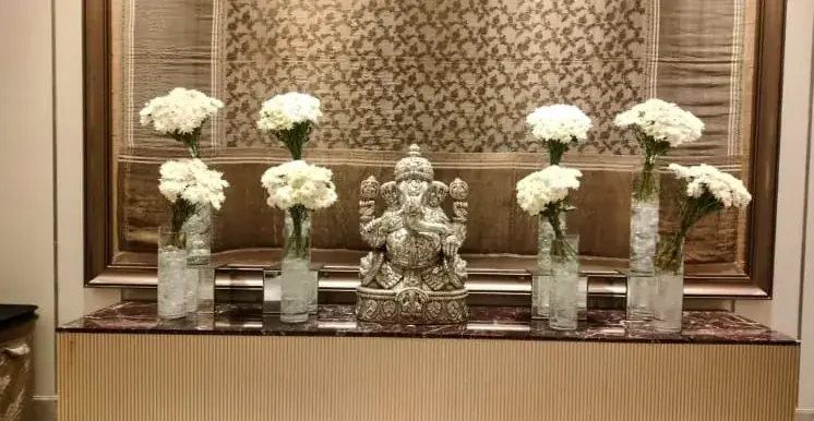 A hotel lobby with white flowers and a carved stone figure