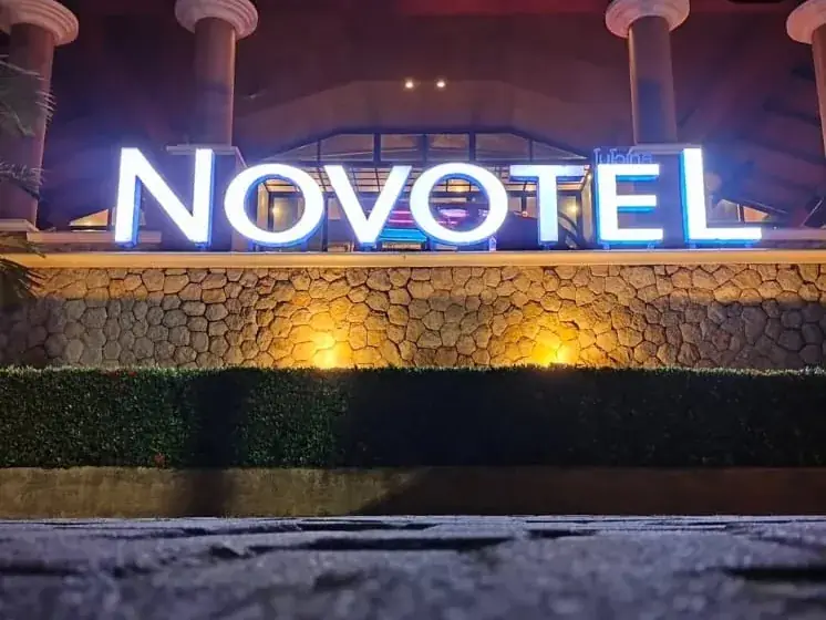 An illuminated hotel sign above a stone wall at night