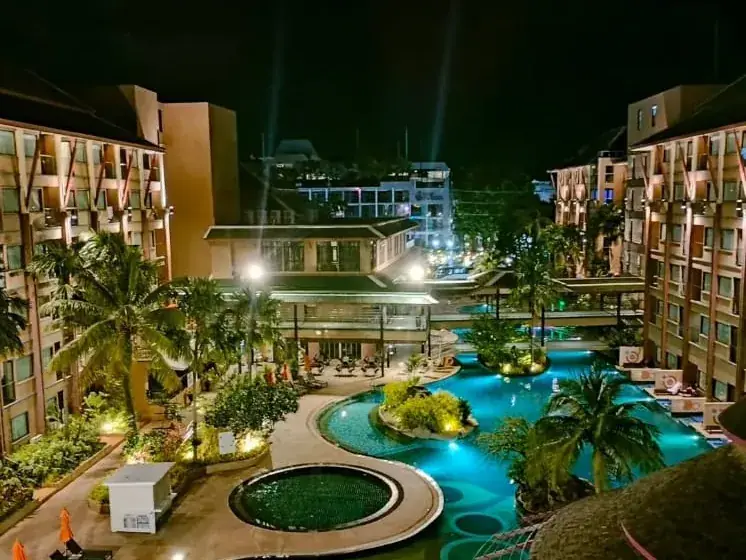 A resort at night with a lit pool and terraces